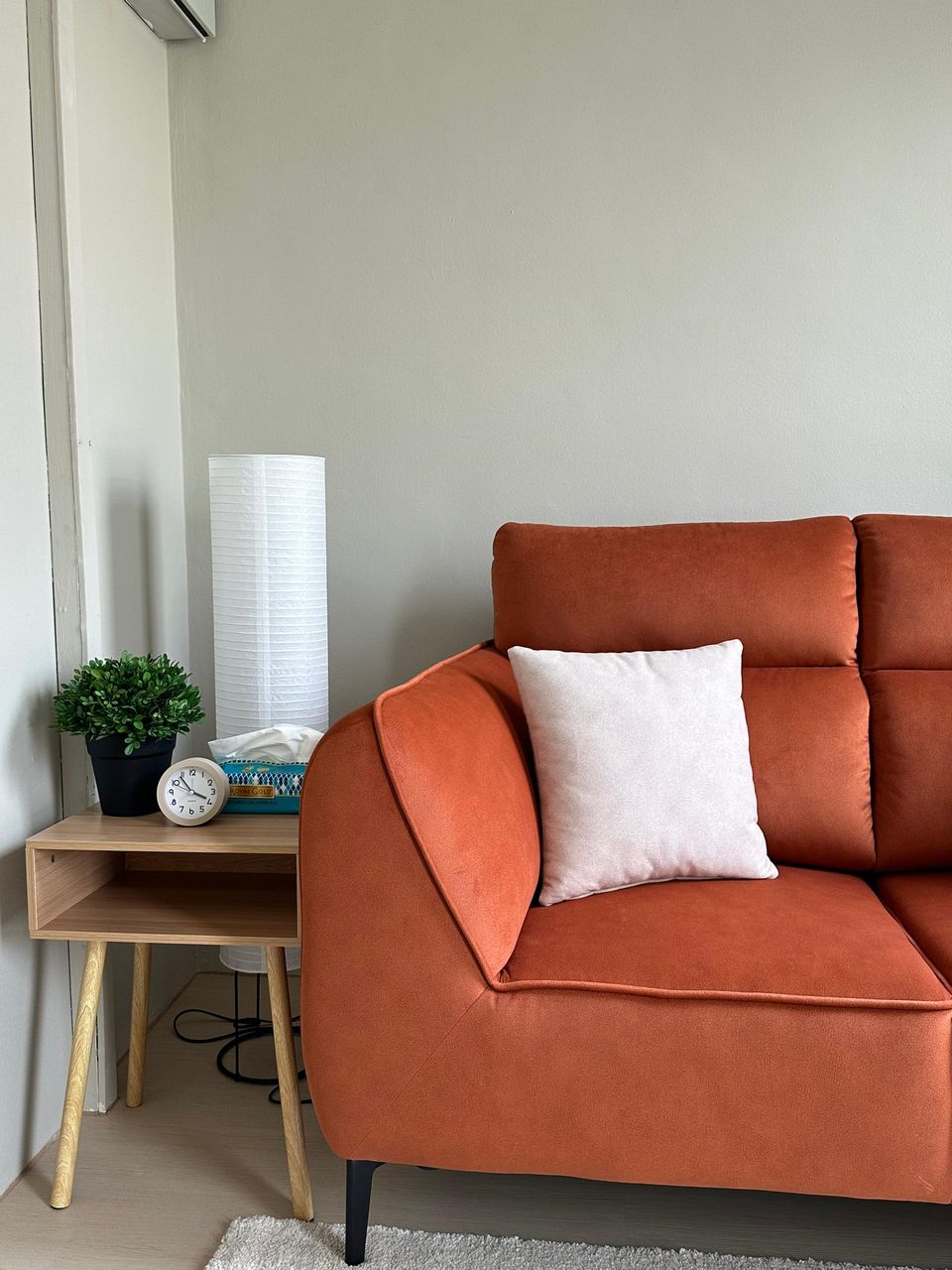 A close view of the rust-orange sofa in the Beige Room, with a white cushion and a small side table