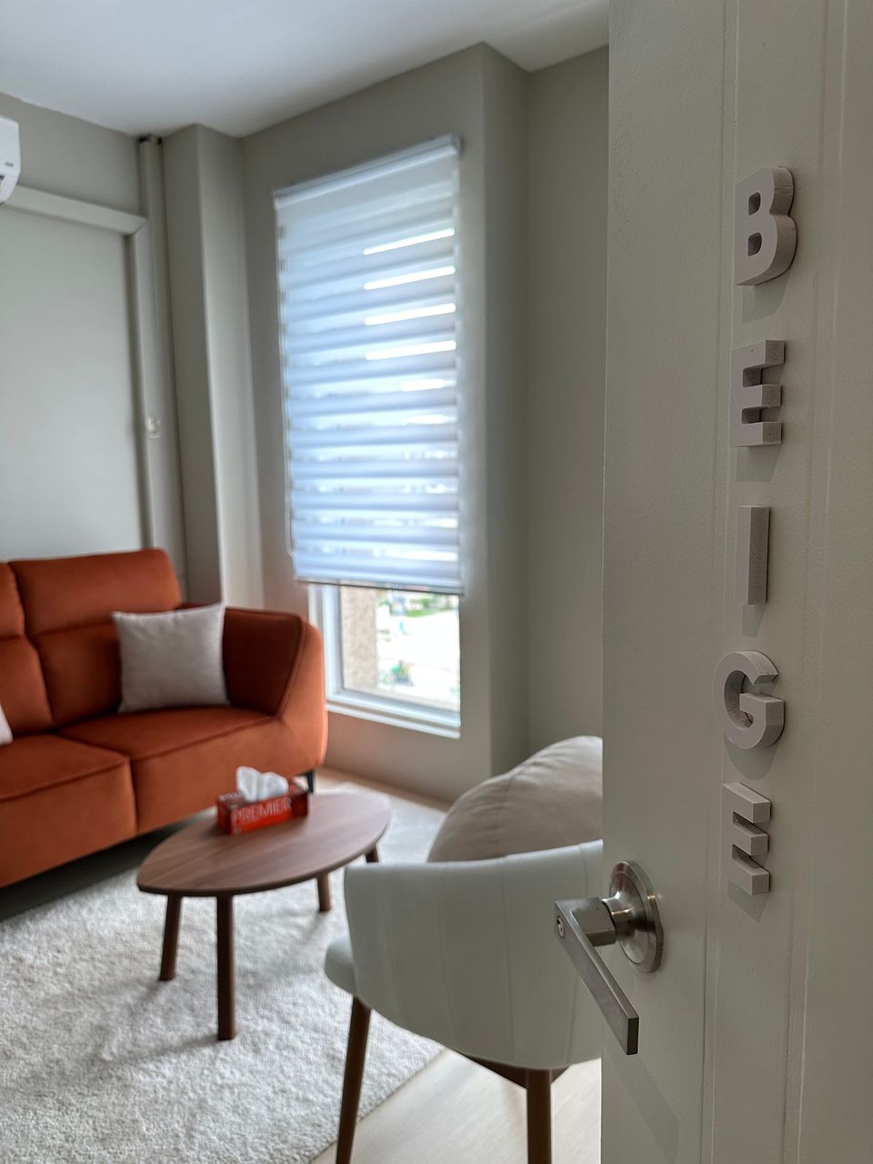 The Beige Room door standing open, BEIGE lettered down the door, the rust-orange sofa beyond