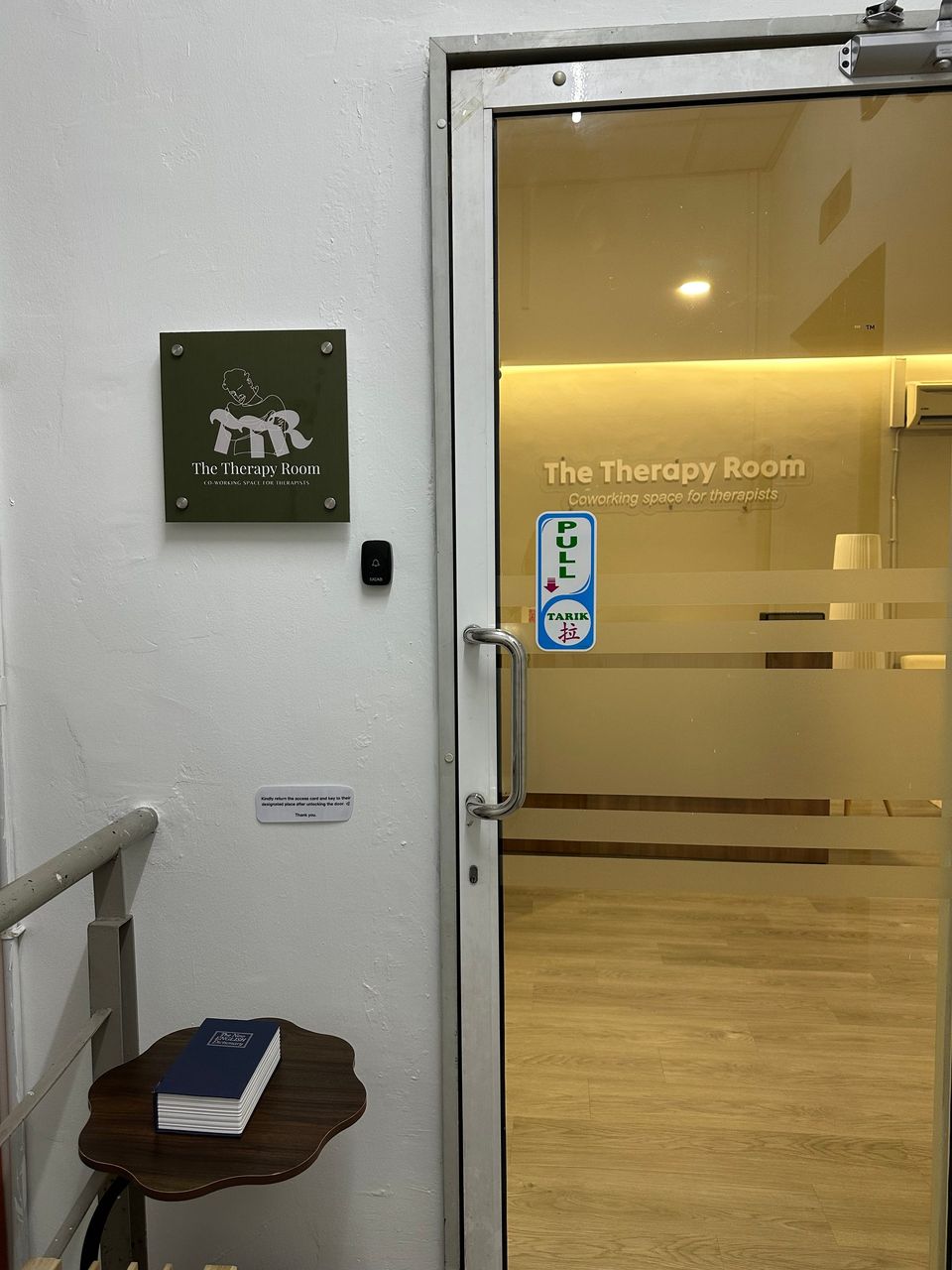 The glass entrance of The Therapy Room, with the olive logo plaque on the wall beside the door