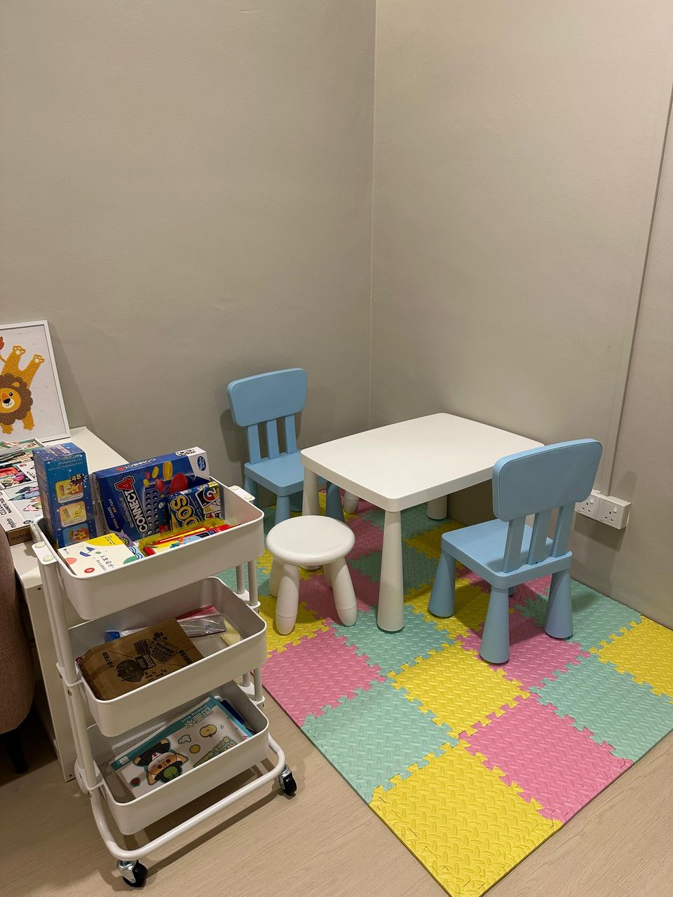 A close view of the Family Room play corner: a child-sized table and chairs, a toy cart and a foam mat