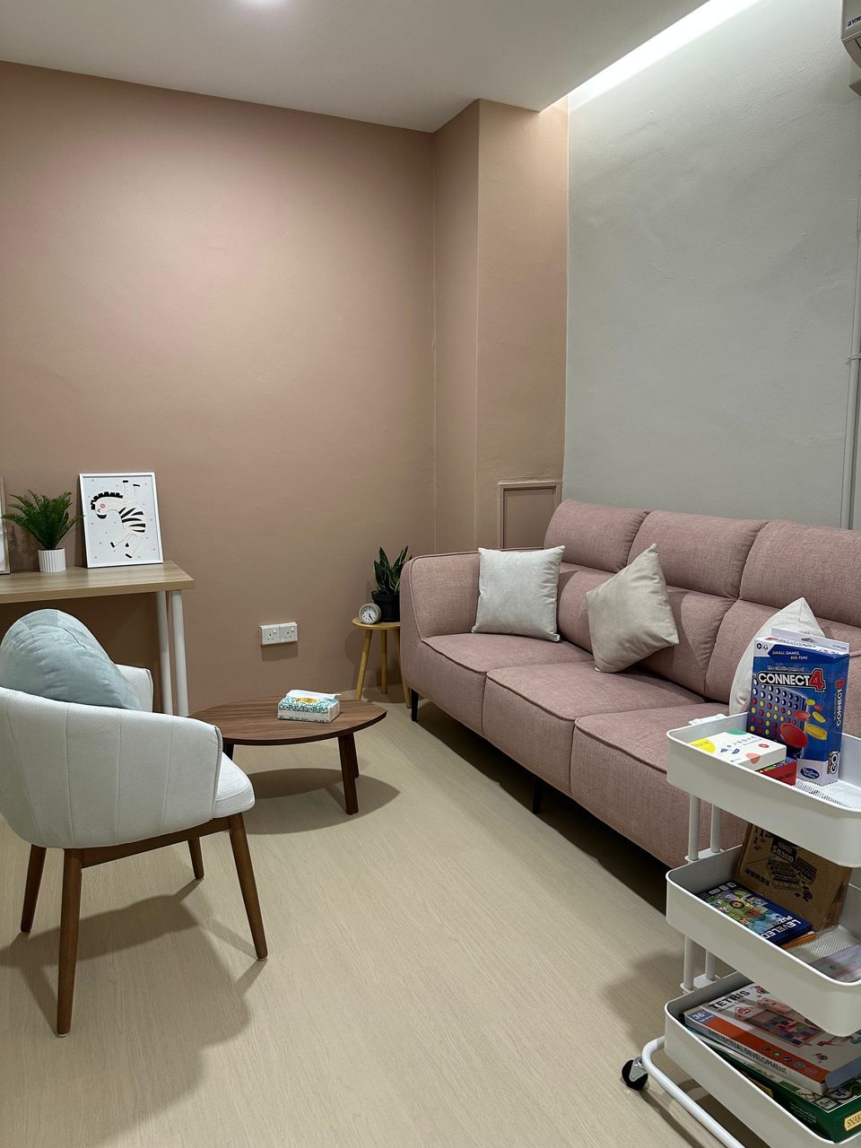 The Family Room: a dusty-pink sofa against a rose wall, an armchair and a cart of toys and books