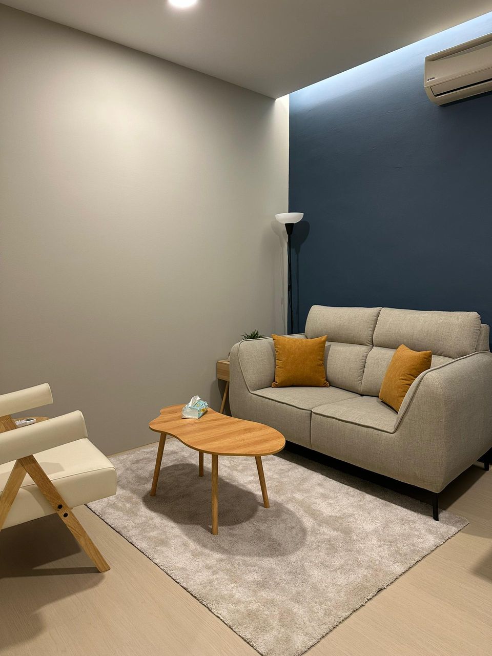 A wider view of the Navy Room, with the sofa, two small wooden tables and an armchair on a soft rug