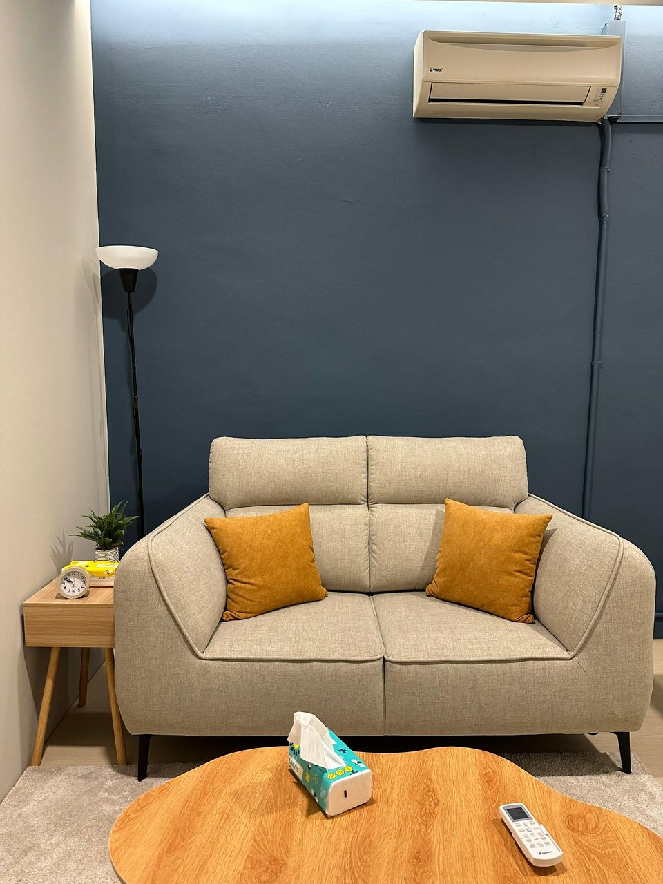 The Navy Room sofa with mustard cushions, seen across a round wooden table