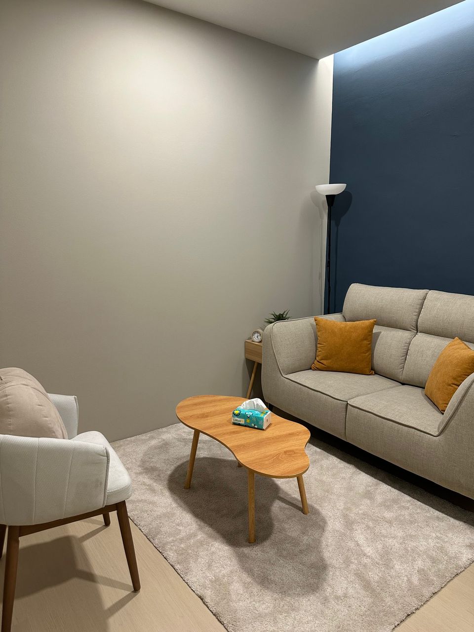 The Navy Room: a beige sofa with mustard cushions against a deep navy wall, a wooden table and an armchair