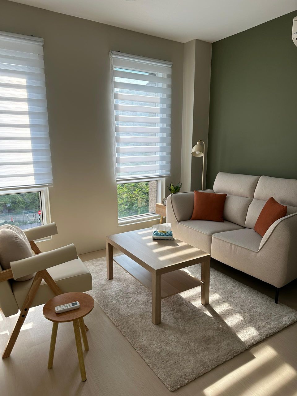 The Olive Room in daylight, with two windows, an armchair, the coffee table and the sofa