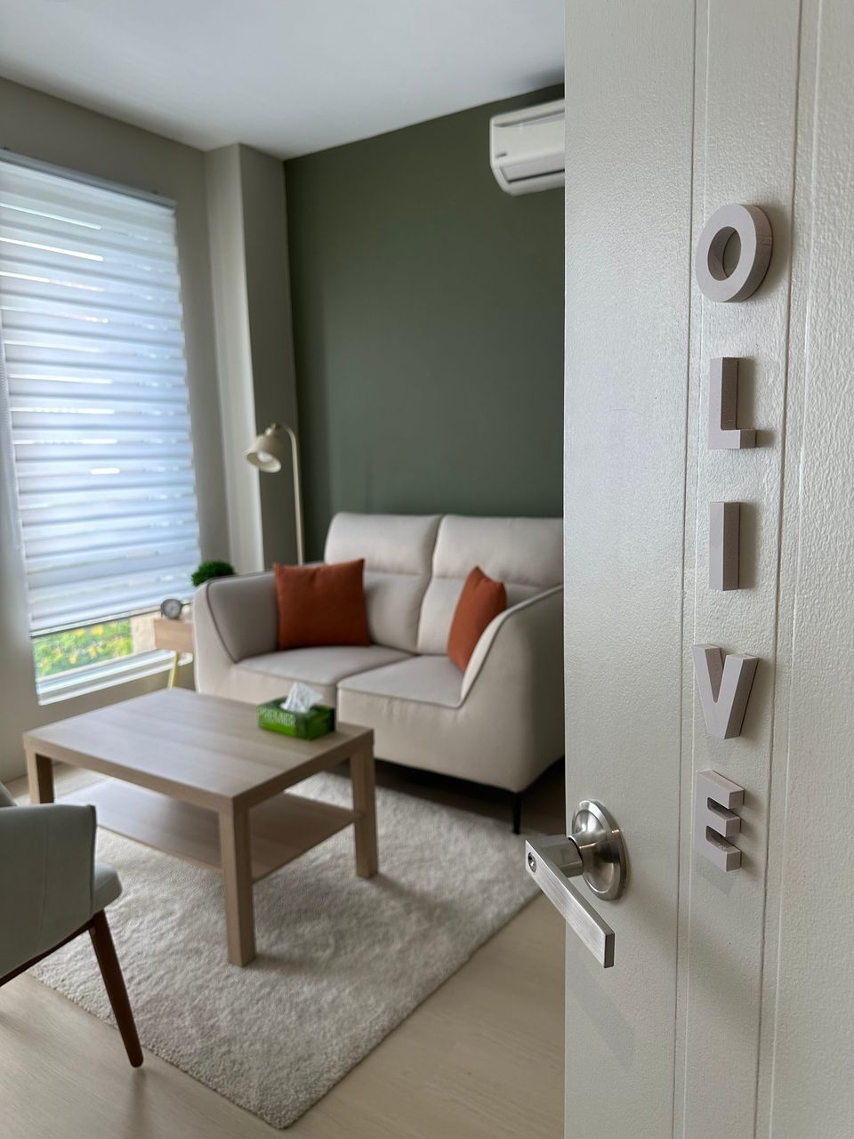 The Olive Room door standing open, OLIVE lettered down the door, the sofa and window beyond