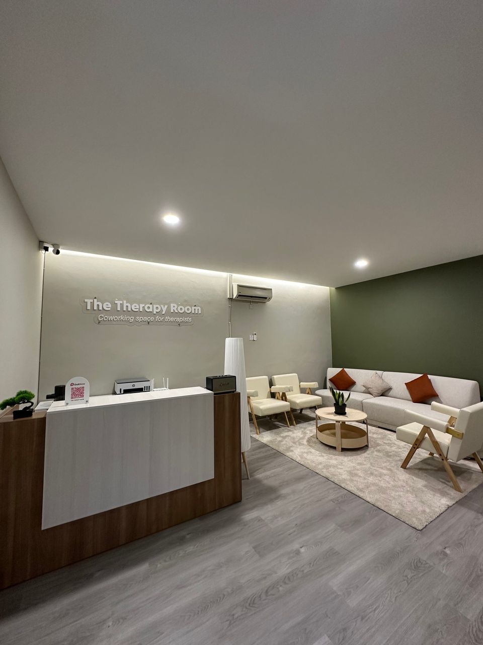 The reception desk under The Therapy Room sign, with a waiting area of sofas and armchairs